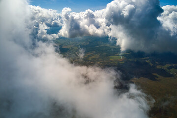 Aerial view from airplane window at high altitude of earth covered with puffy cumulus clouds forming before rainstorm