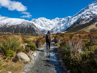 Fototapeta na wymiar Female hiker on the alpine track to Mount Cook New Zealand with view of the snowy mountain range