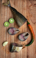 smoked mackerel fish with chilly pepper and lime on wooden background. Smoked fish, mediterranean food, herring fish, seafood, top view