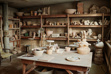 Fototapeta na wymiar Image of workplace of craftsperson with ceramic sculptures on the shelves