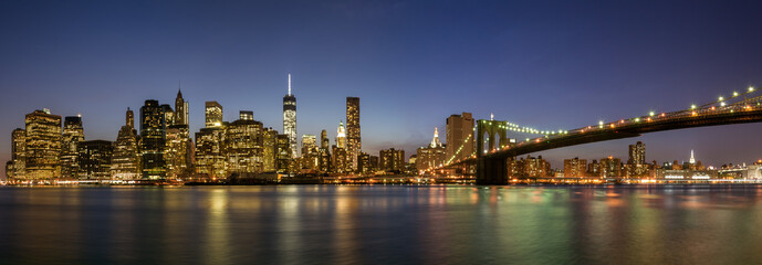 Panoramic view of Manhattan with the Brooklyn Bridge at night.