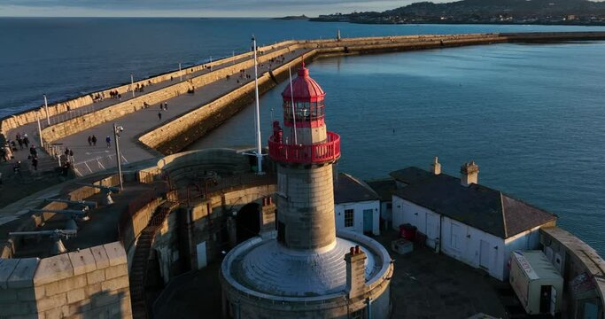 D&uacute;n Laoghaire Harbour, Dublin, Ireland. December 2021 Drone orbits the East Pier lighthouse at a low altitude from the north side with Killiney Dalkey Island Howth and yachts sailing in the distance.