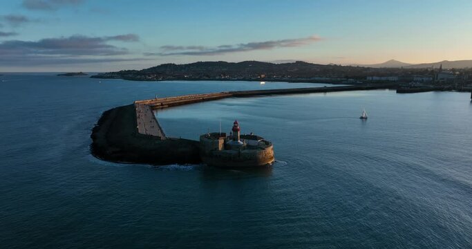 D&uacute;n Laoghaire Harbour, Dublin, Ireland. December 2021 Drone orbits the East Pier lighthouse from the north at a higher altitude with Killiney Hill and Dalkey Island in the distance.