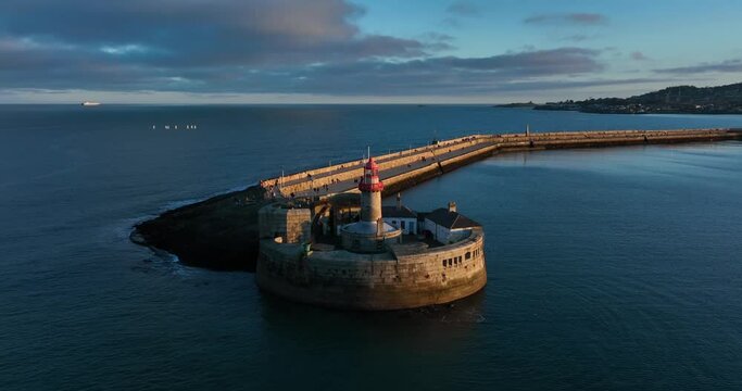 Dún Laoghaire Harbour, Dublin, Ireland. December 2021 Drone orbits the East Pier lighthouse while pushing closer from the northwestern side with Killiney and Dalkey Island in the distance.