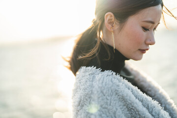 冬の夕暮れの海にいる女性