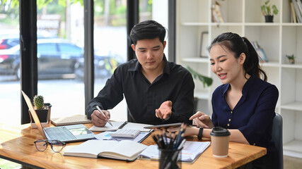Two young business people discussing project strategy at meeting room.