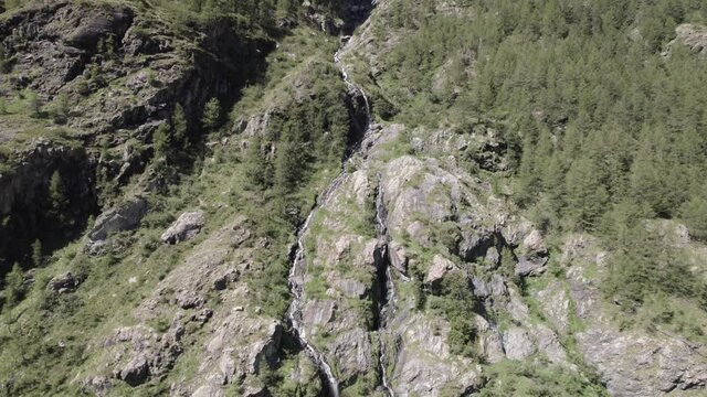 video of crane plane or ascent with bird's eye view at the end with drone flying over a waterfall in the italian alps