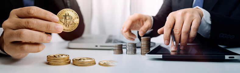 Businesswoman holding a lightbulb while taking note on notebook with coins stack on table, saving energy and money concept