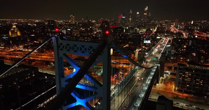 Aerial of Ben Franklin Bridge at night in Philadelphia. Philly city lifestyle in evening. Dramatic view with cityscape lights.