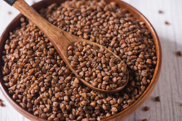 close up of dry buckwheat in spoon on table