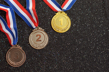 Gold, silver and bronze medals with numbers One, Two, Three and ribbons.