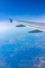 Fototapeta premium View from the airplane window at a beautiful blue clear sky and the airplane wing