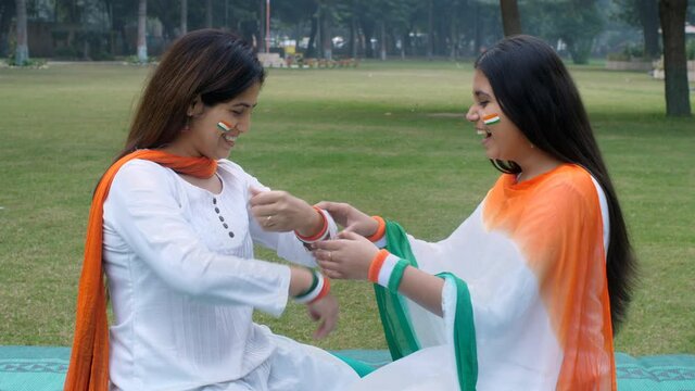 An attractive lady wearing tricolor bangles on the occasion of Republic Day. Two females dressed up in Indian tri colors sitting on the park - Independence Day  patriotic mood  traditional dress
