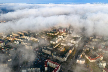 Top aerial view of fluffy white clouds over modern city with high rise buildings