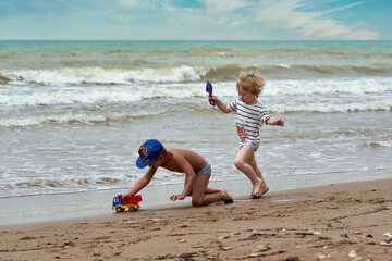 Two little boys are playing on the seashore - 477244760