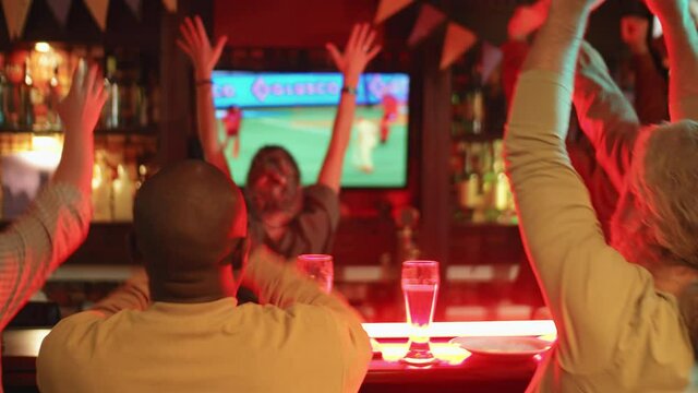 Back view shot footage of modern football fans spending evening in pub enjoying watching match