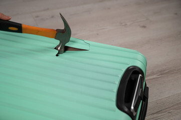 A woman hits a suitcase with a hammer on a white background.