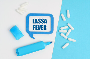 On a white and blue table are pills, a marker and a blue plaque with the inscription - Lassa fever