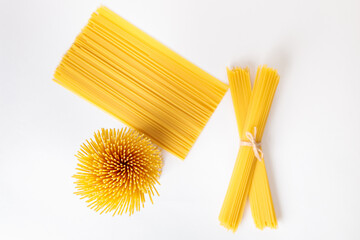 A vertical bunch and a bunch of raw spaghetti tied with string. Bundle on a white background. View...