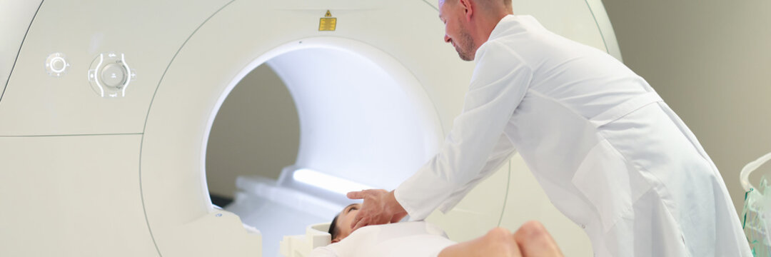 Doctor helping woman to lie down in mri machine in clinic