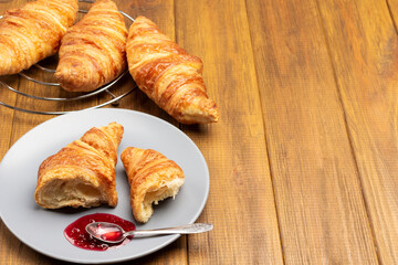 Croissant halves and spoon with jam on saucer.