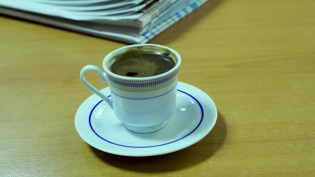 Turkish coffee and daily newspapers in the background on wooden table.