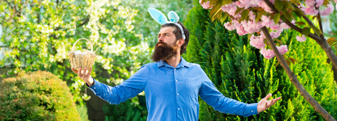 Easter egg hunt concept. Humorous series of a man in bunny suit. Good for Easter or ironic situations. Bunny man having fun in park. Banner.