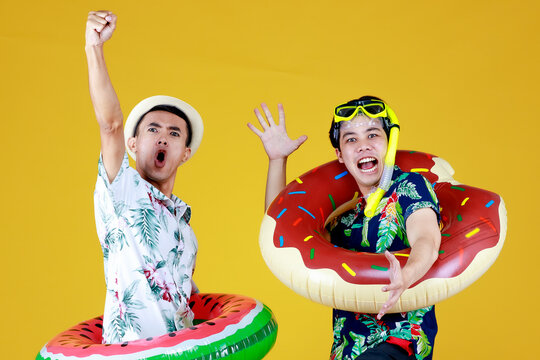 Happy Asian guys enjoy summer holiday festival as party entertainers by playing funny dance for carnival with ball float and snorkel for joyful scuba diving
