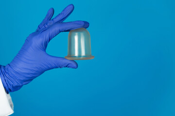 Doctors hand in a glove holds a vacuum massage jars on a blue background close-up
