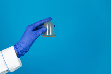 Doctors hand in a glove holds a vacuum massage jars on a blue background with copy space.