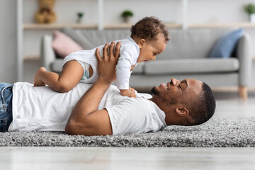 Father's Love. Happy Young Black Dad Bonding With Newborn Baby At Home - obrazy, fototapety, plakaty