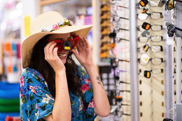 Woman laughing while trying on sunglasses in a store