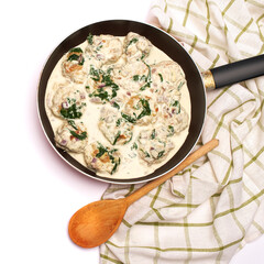Delicious small meatballs with spinach in a creamy sauce in the frying pan