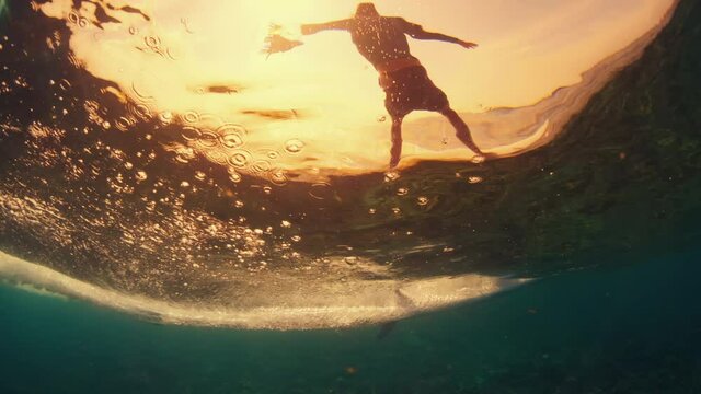 Surfer rides the ocean wave in tropical Maldives, split view of the surfer and underwater view of the rolling and breaking wave