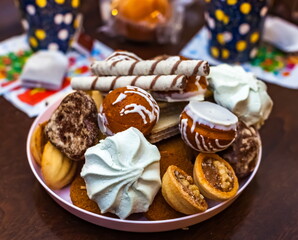 Confectionery on a plate on a dark table close-up against the background of paper cups
