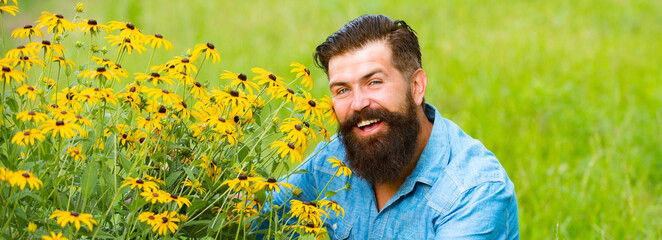 Spring banner of man outdoor. Smiling man with flowers. Spring mood. Sunny portrait. Carefree and positive thinking. Rudbeckia flower.