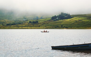 Beautiful morning landscape scenery with people canoeing at Loch na fooey with green mountains in...