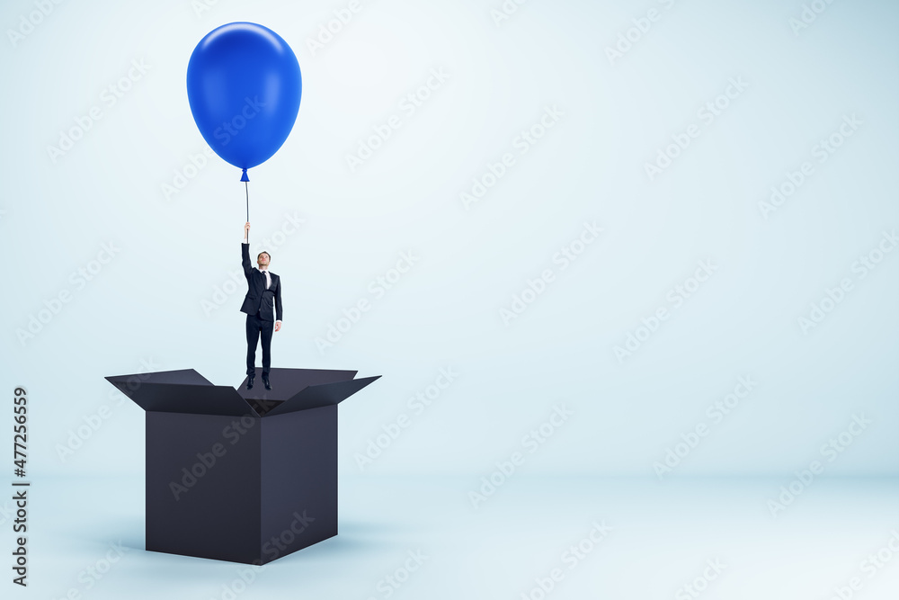 Poster abstract image of young european businessman flying on blue balloon out of black paper box on light 