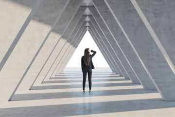 Back view of businesswoman in abstract concrete triangle corridor. Space and hallway concept.