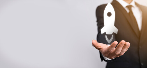 Startup business concept, Businessman holding tablet and icon rocket is launching and soar flying out from screen with network connection on dark background.