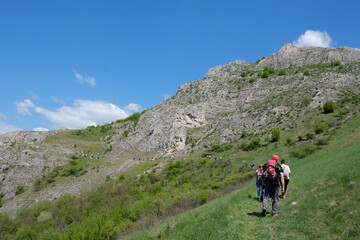 Fototapeta na wymiar Beautiful mountain landscape in spring and hikers hike thru green scenery