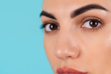 Beauty portrait of a young woman in a blue knitted sweater and natural day makeup, full lips with nude matte lipstick and perfect eyebrows