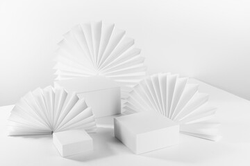 White light abstract scene with three different square podiums on table mockup as showcase for displaying, presentation cosmetic product, goods with asian ribbed paper fans, side view, corner, 3d.