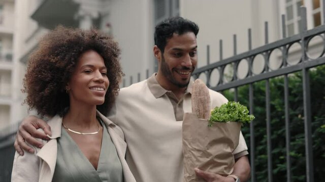 Positive couple with grocery bag walking together on street