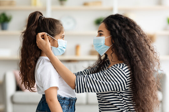 Side View Of Woman Putting Face Mask On Her Daughter