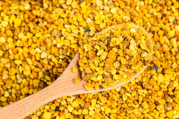 top view of wooden spoon with natural bee pollen on bee bread
