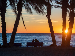 Pareja de novios sentados frente al mar contemplando la puesta de sol en La Herradura