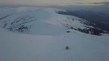 Dragobrat, Ukraine - March 29, 2021: Ratrak descends down the snow-covered mountainside in the morning