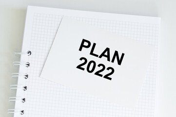 Plan 2022 inscription on a card that sits on a white blank notebook on the table