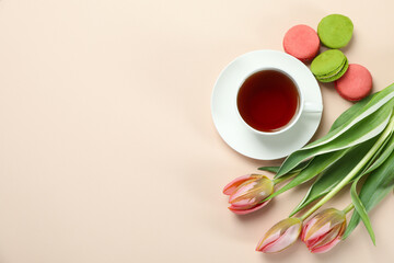 Tea, tulips and macaroons on beige background